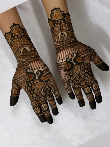 A graceful design featuring symmetrical peacocks on both hands, with lotus motifs on the wrist. The darkened fingertips complete this classic bridal look.