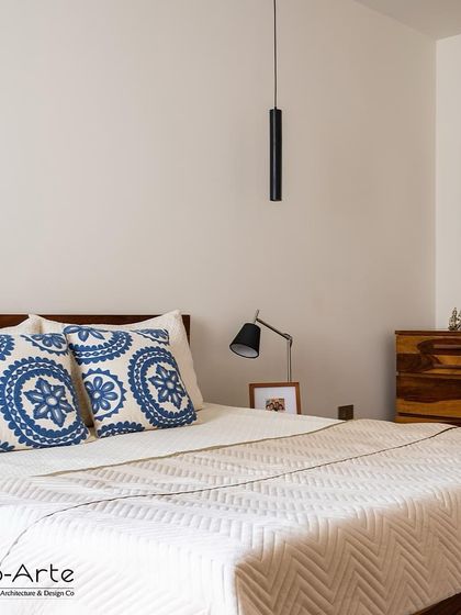 Part of the Minimalist Haven project, this bedroom features soothing hues for tranquil nights. The simple wooden bed frame and patterned blue cushions add a touch of calm elegance.