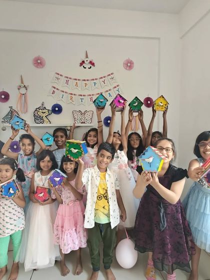 The whole group from Emma's party proudly holding up the colorful birdhouses they created.