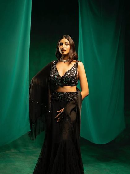 A shot from the 29 India campaign featuring a black layered lehenga. The draped green fabric in the background was part of the set styling to add depth and color contrast.