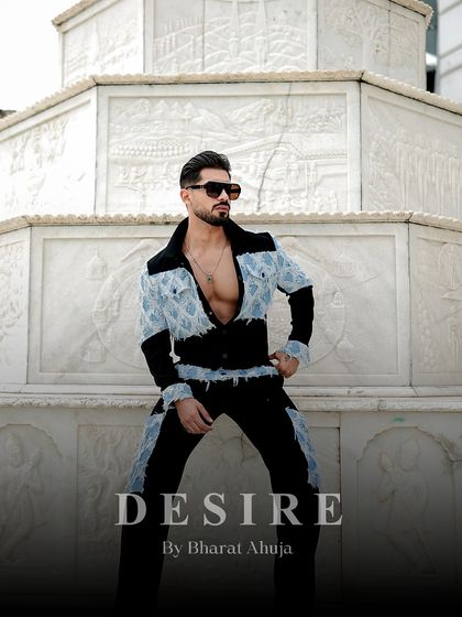 A powerful pose in the black and denim patchwork set. The unbuttoned jacket reveals a confident physique, while the distressed denim adds a rebellious edge.