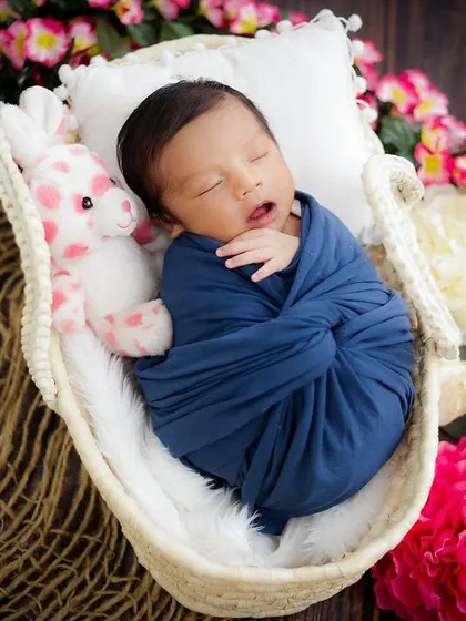 A peaceful newborn tucked into a basket with a plush toy and surrounded by flowers. I use a mix of props to add color and texture to the scene.