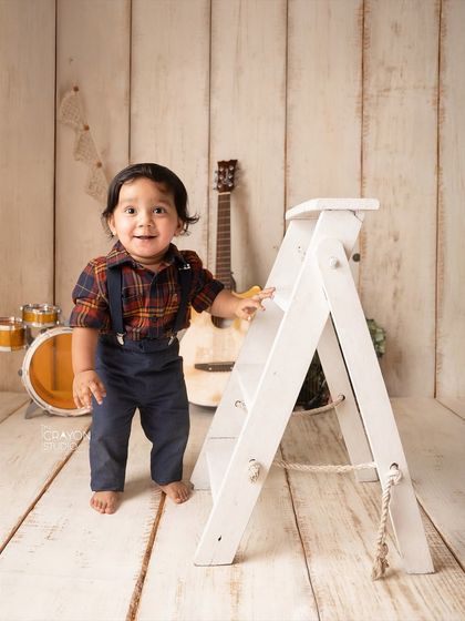 This little rockstar is already learning to stand, using a prop ladder for support during his music-themed photoshoot.