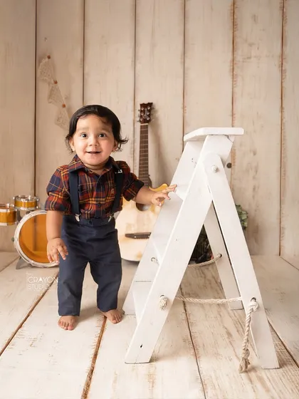This little rockstar is already learning to stand, using a prop ladder for support during his music-themed photoshoot.