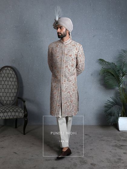 A full-length view of the coffee-beige sherwani, showing its structured silhouette and how it pairs with classic churidar pants, embodying modern royalty.