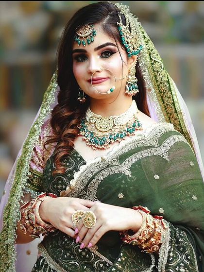 A bride in a dark green lehenga with a matching Kundan choker and passa. This is a sophisticated and elegant look for a wedding or reception.