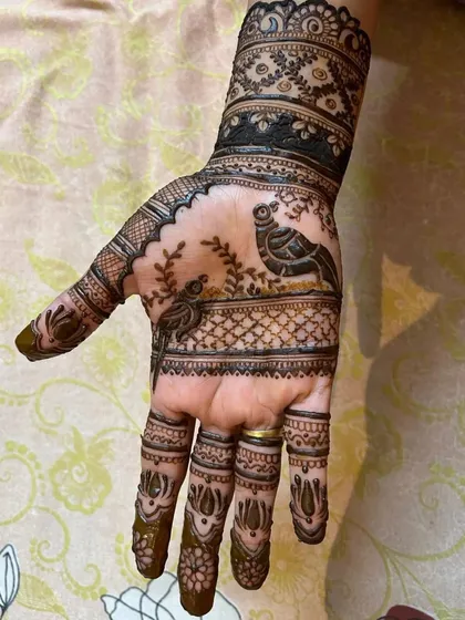 A clear view of a traditional Rajasthani mehndi design with two birds perched on a branch. This kind of figurative work is a lovely way to add a narrative to your bridal henna.