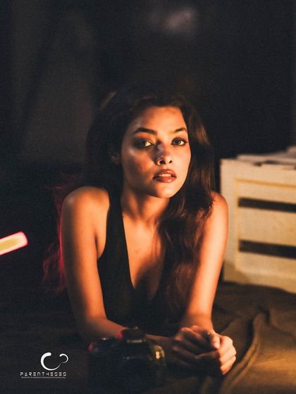 A direct and engaging portrait. Her clasped hands and steady gaze create a sense of quiet strength and determination.