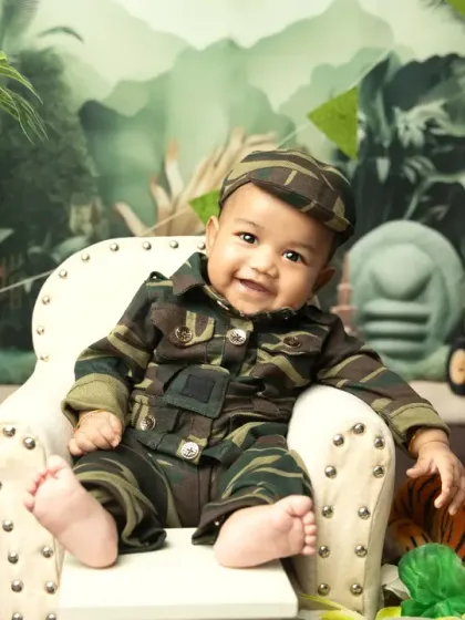 A proud little soldier sitting in his chair, surrounded by a jungle and tiger props for an Independence Day theme.