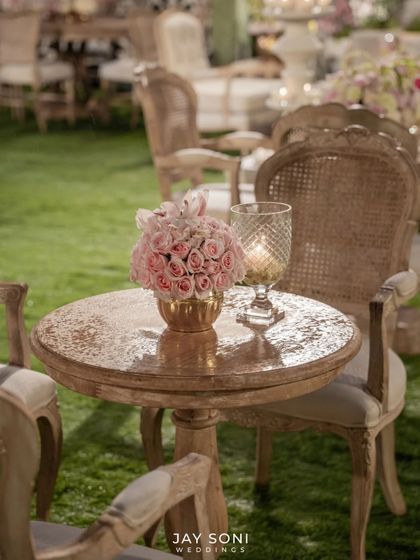 A simple yet elegant detail. A small bouquet of pink roses in a gold vase sits beside a crystal-cut candle holder, adding a touch of romance to a side table.