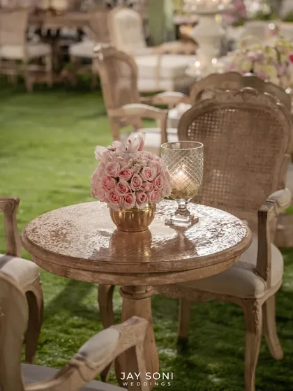 A simple yet elegant detail. A small bouquet of pink roses in a gold vase sits beside a crystal-cut candle holder, adding a touch of romance to a side table.