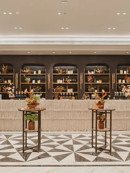 The bar design for the carnival event featured natural textures and a warm, candlelit back bar, blending seamlessly with the elegant and earthy decor.