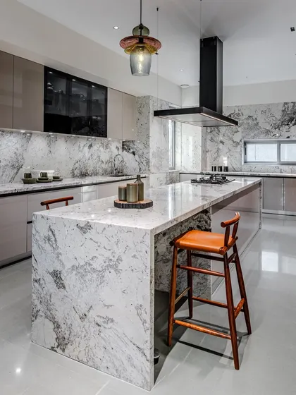 This perspective of Khyati Patel's kitchen highlights the striking contrast between the white marble island and the warm walnut cabinetry, a perfect example of mixing materials for a luxurious effect.