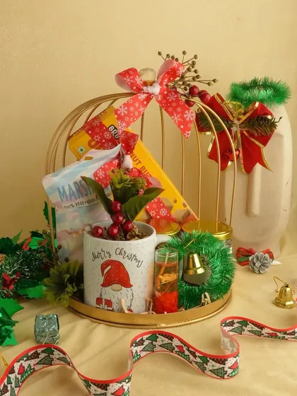 A festive Christmas hamper in a golden birdcage. This unique presentation holds a Santa mug, marshmallows, and other treats, making it a whimsical and memorable gift.