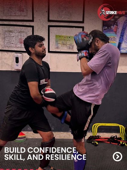 A coach holds pads for a student, guiding them through a kicking combination. This one-on-one attention helps build confidence, skill, and resilience.