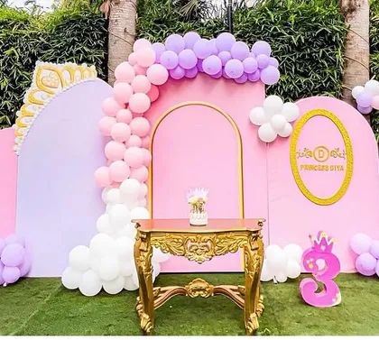 The main stage for a princess's third birthday. The setup includes pastel pink and purple backdrops, a golden ornate table, and a personalized name plaque, creating a magical outdoor photo area.