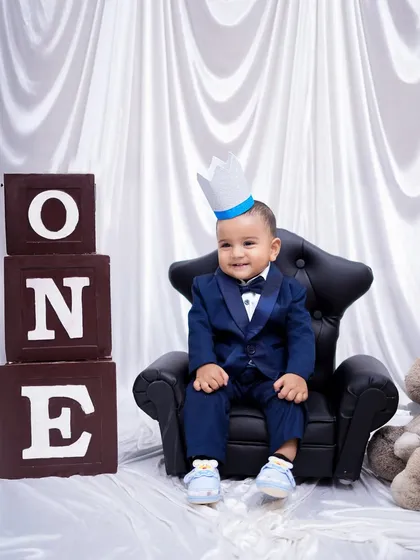 A little prince on his throne. Dressed in a smart blue tuxedo, this one-year-old is ready to celebrate his birthday milestone in style.