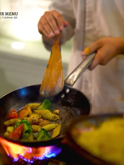 A chef stir-frying fresh vegetables over a high flame, demonstrating the dynamic and engaging nature of our live cooking stations.