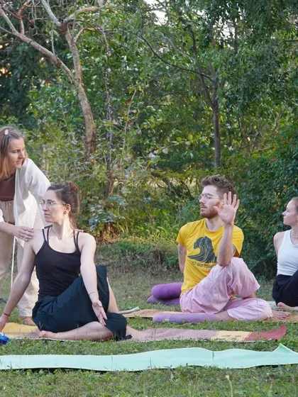 Teaching practice begins early in our programs. Here, a student practices giving adjustments for a seated spinal twist, learning how to guide her peers with confidence and clarity in an outdoor setting.