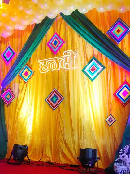 A closer look at the Haldi stage backdrop, featuring a neon sign and colorful decorative elements against yellow drapes.