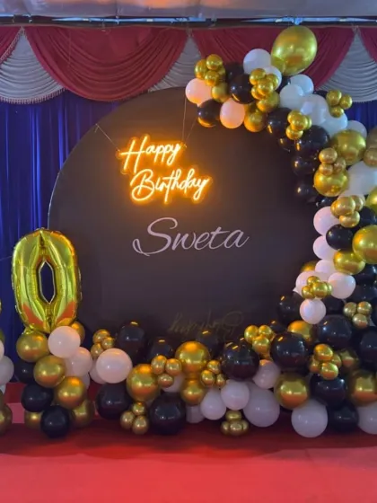 Celebrate a 50th birthday in style with our custom party backdrops. This setup includes a personalized circular backdrop with a neon 'Happy Birthday' sign, a large '50' marquee number display, and a sophisticated black, gold, and white organic balloon arch.