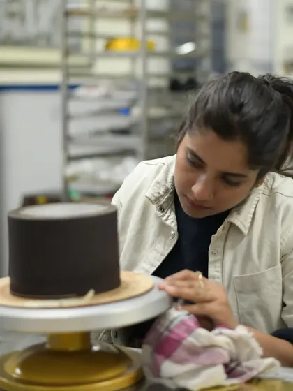 Focused on the details. Here I am, working on a chocolate-wrapped cake, ensuring the finish is smooth and perfect.
