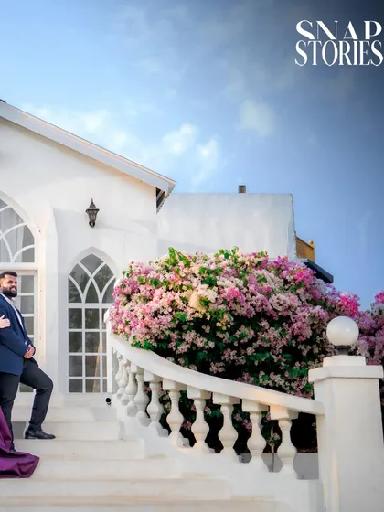 A wide shot capturing the couple on a grand staircase, framed by lush bougainvillea. This composition highlights both the romance and the beauty of the location.