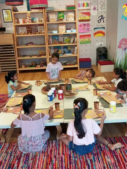 A playdate group works on a painting project together, learning to share space and materials.