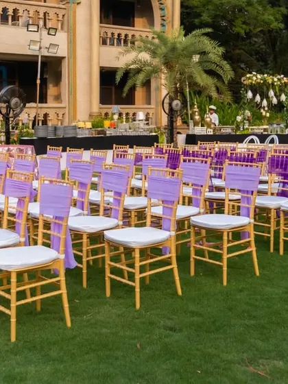Another view of the meticulously arranged seating. The combination of gold chairs with light purple and deep purple sashes created a beautiful gradient effect across the lawn, showcasing a thoughtful approach to event design.