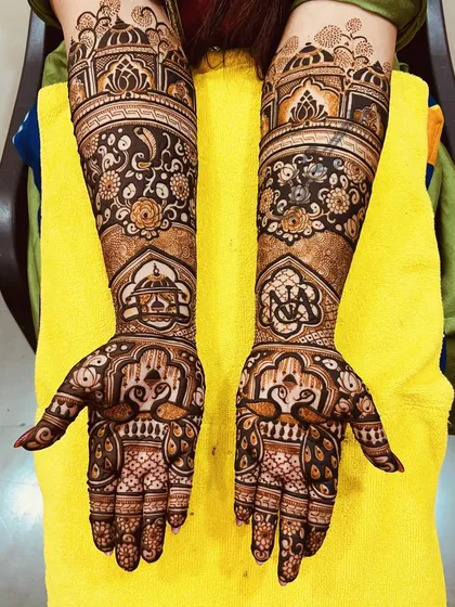 A stunning floral and architectural design. This mehndi combines the softness of rose patterns with the grandeur of palace domes, along with peacock figures on the palms.