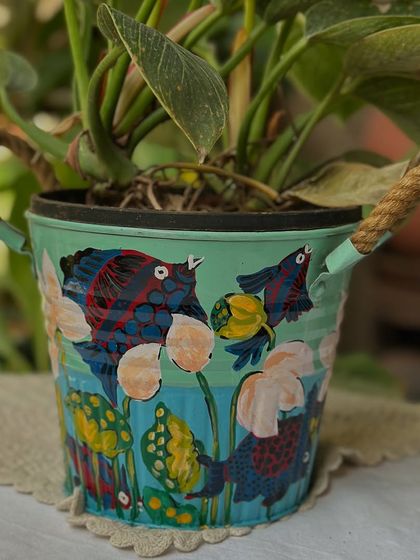 This planter from the same collection features a playful underwater scene with whimsical fish painted on a soft green background.