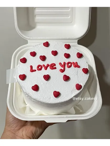 A classic 'Love you' bento cake with red text and matching red hearts on a clean white frosting base.