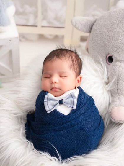 A close-up of a newborn swaddled in blue, with a tiny bowtie added for a dapper touch. This small detail shows how we add personality and charm to our themed setups.