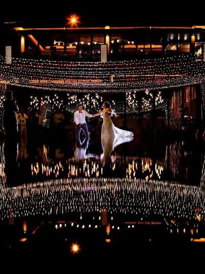 A magical first dance under a canopy of fairy lights. The reflection on the water adds a layer of enchantment to this incredibly romantic and cinematic moment.
