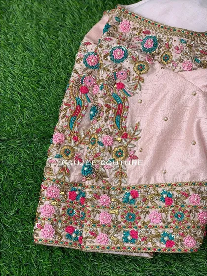 A detailed view of the sleeve of the pink peacock blouse. You can see the texture of the threadwork and the careful placement of beads that bring the traditional motifs to life.