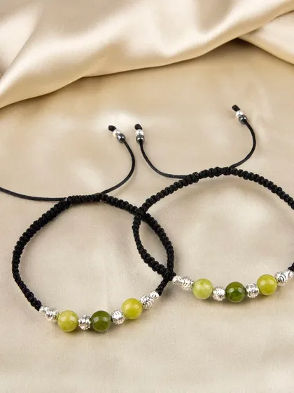 A pair of adjustable anklets with green beads and silver accents.
