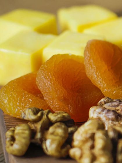 A close-up shot focusing on the rich textures of dried apricots, walnuts, and cubed cheese on a platter. This highlights the quality of the individual components of my boards.