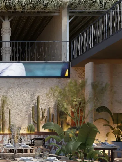 This view shows the layered design of Skyro, with a mezzanine level overlooking the main dining area. The mix of textures, from the thatched roof to the rough walls and lush plants, creates a rich and immersive environment.
