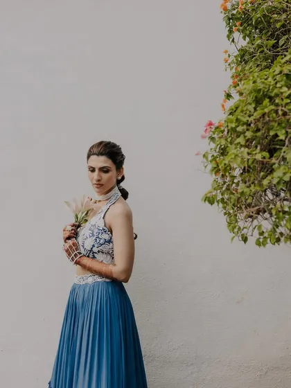 A minimalist portrait of the bride-to-be, holding a flower, against a clean white wall.