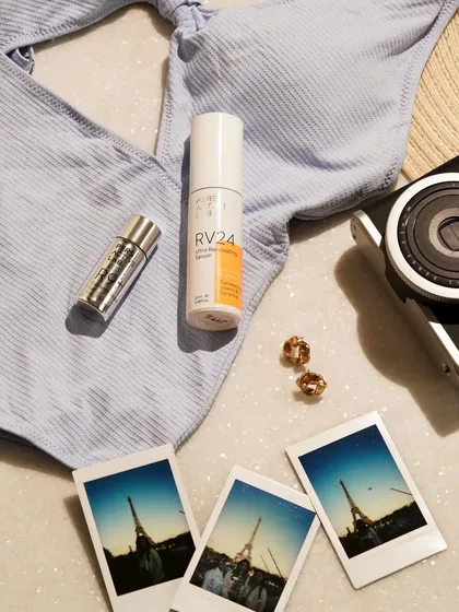 This travel-themed flatlay includes a swimsuit, polaroids, and earrings alongside the skincare products. It tells the story of a vacation, positioning the items as essential travel companions.