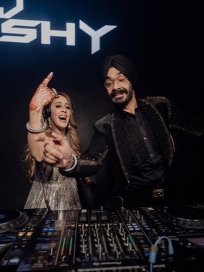 Power couple goals. The groom is ready for the cocktail party in a custom black jacket with shimmering, structured beadwork on the shoulders, perfectly complementing his bride's sparkling gown.
