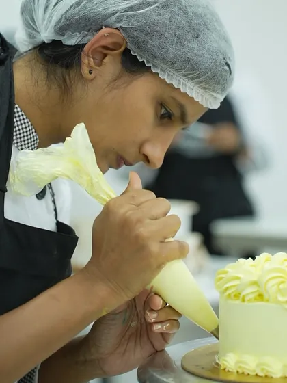 Here, I am guiding a student as she perfects her piping technique. In my class, you get complete hands-on practice, and I am right there to help you master the skills needed for professional cake and cupcake decoration.