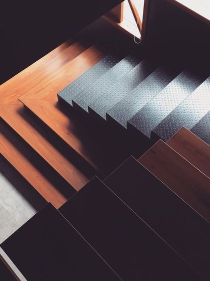 The beauty of contrasting materials in a staircase design. The transition from dark wood to textured steel treads creates a sharp, modern, and edgy look.