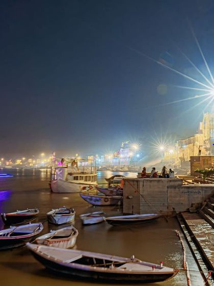 A long-exposure shot of the ghats during Dev Deepawali. The starburst effect of the lights and the light trails from the boats create a magical, dreamlike image of Varanasi at night.