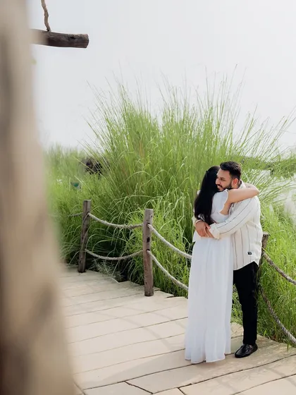 A candid and intimate embrace on a wooden bridge, framed by the natural surroundings.