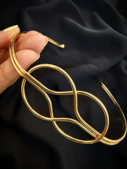 A close-up product shot of the Layla Lotus gold Hasli, highlighting its intricate and modern knot design.