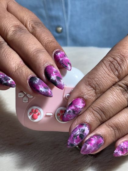 A beautiful example of purple marble nail art. The swirling blend of purple, black, and white creates a unique and artistic look on every nail.