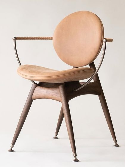 This chair design is an inspiration for what's possible with mixed materials. It features a solid wood base, a metal frame, and a circular leather-upholstered back and seat for a unique, modern look.