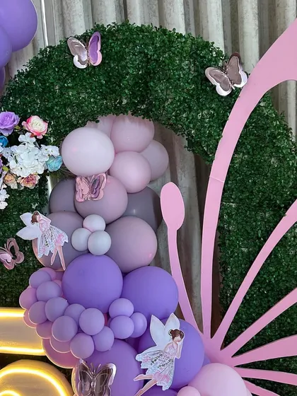A beautiful detail shot where the faux-grass arch, balloon arrangement, and butterfly wing prop meet. This image shows the seamless integration of different materials and textures to create a visually stunning focal point.
