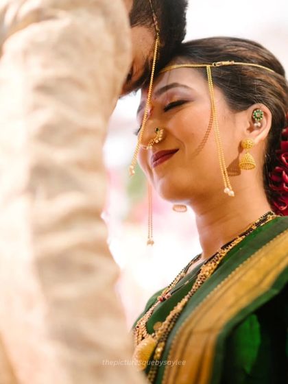 A beautiful, tender moment during a Maharashtrian wedding ritual. The bride's expression shows the mix of emotion and happiness that fills the day.